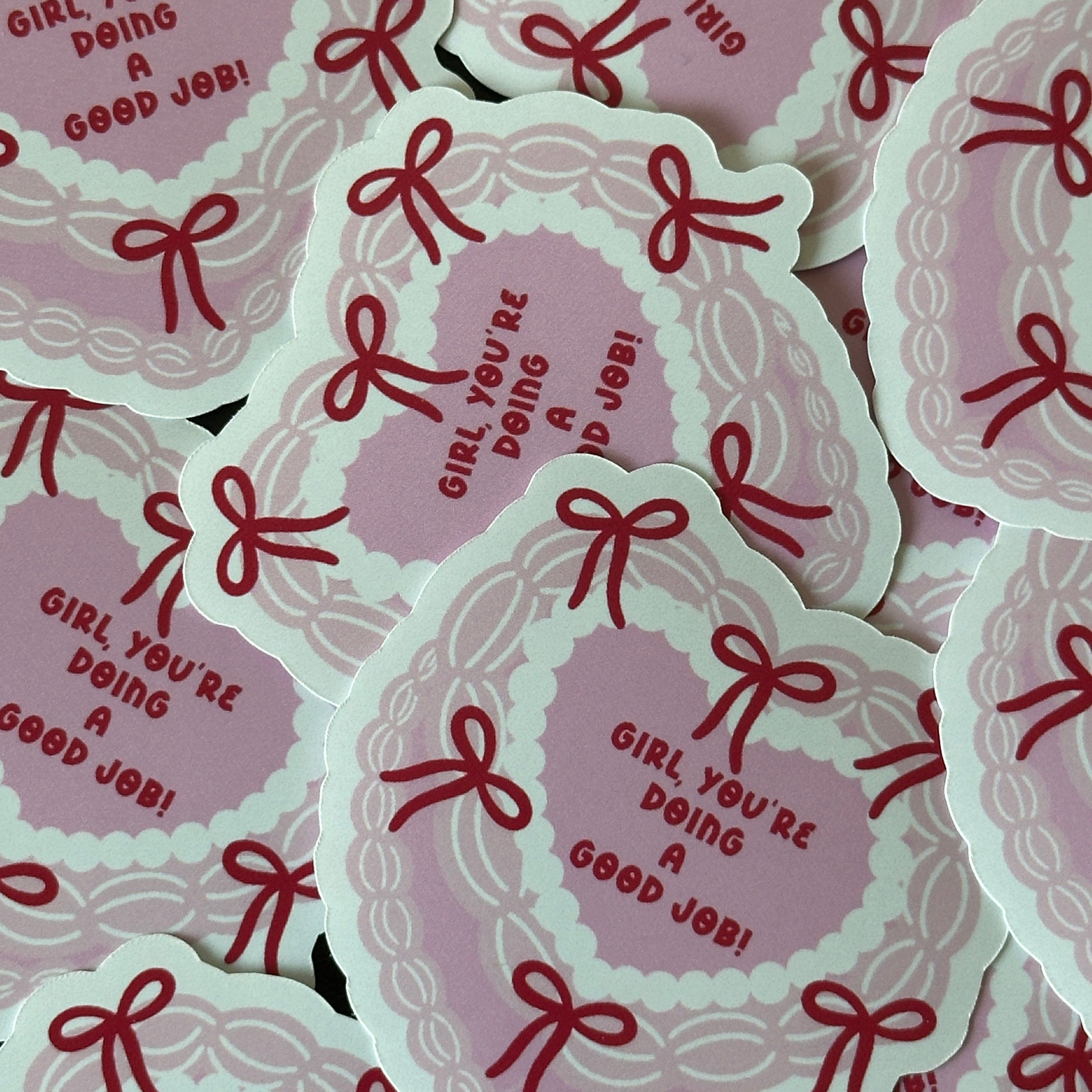 "Glossy pink heart-shaped vinyl sticker bordered with red bows and the message 'Girl, you're doing a good job!'"